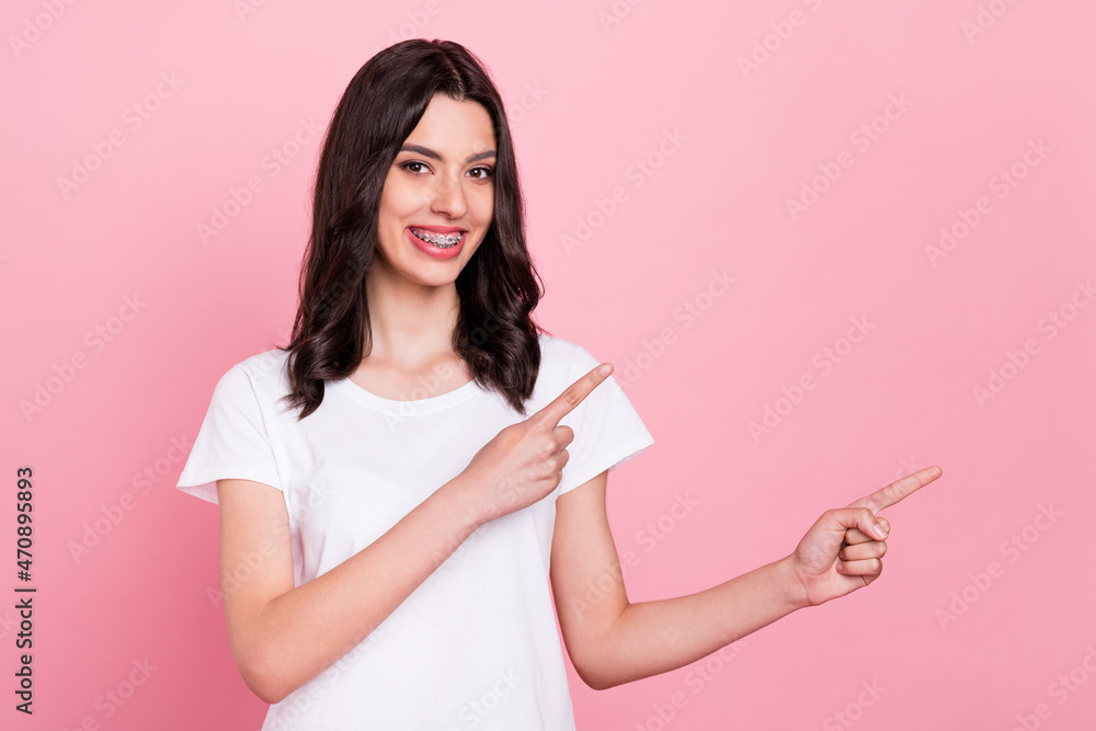 Photo of positive young happy charming woman point fingers empty space smile isolated on pink color background Photo of positive young happy charming woman point fingers empty space smile isolated on pink color background