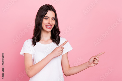 Photo of positive young happy charming woman point fingers empty space smile isolated on pink color background