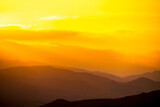 Yellow sunset in the layers of mountains