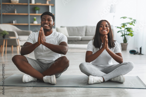 Black couple meditating keeping hands together in prayer pose