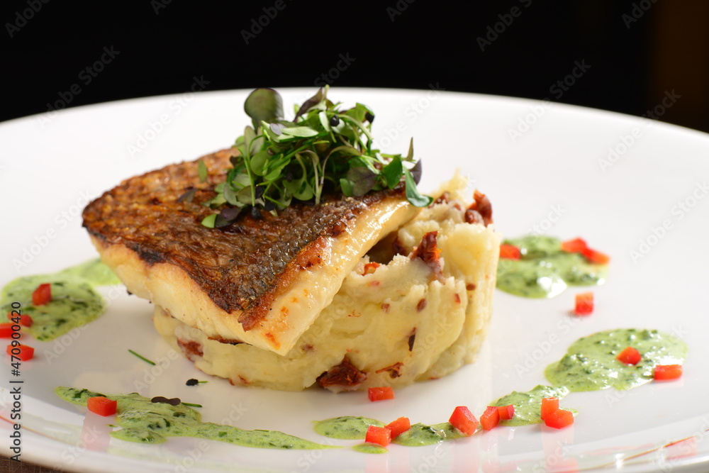 Tasty healthy fish fillet with potato puree with dried tomatoes and wild garlic sauce