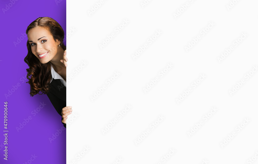 Happy excited woman in black confident suit, peek out showing mock up blank white banner signboard with copy space for sign text. Business ad concept. Violet purple color background. Happy excited woman in black confident suit, peek out showing mock up blank white banner signboard with copy space for sign text. Business ad concept. Violet purple color background.