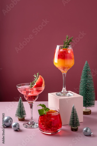 Festive citrus cocktails on podiums. Assortment of fresh Christmas drinks. Pink and red sangria cocktails, pomegranate  jingle and citrus tequila smashy. photo