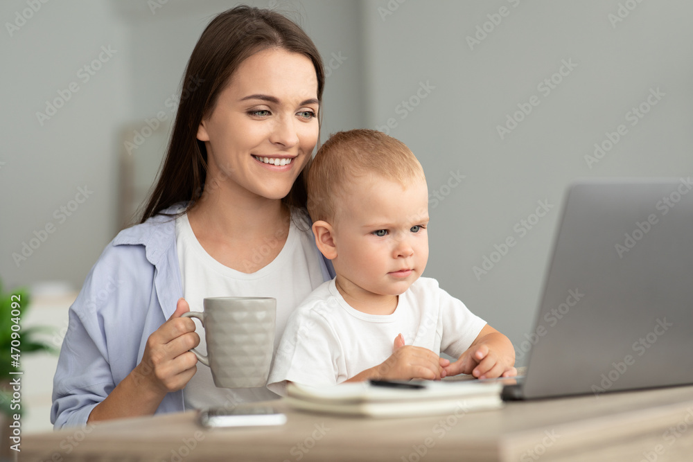 Technology And Childcare. Mother Drinking Tea While Baby Watching Cartoons On Laptop Technology And Childcare. Mother Drinking Tea While Baby Watching Cartoons On Laptop