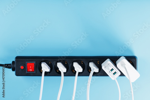 Fotografie Electric mains filter with inserted white plugs of electrical appliances on a blue background