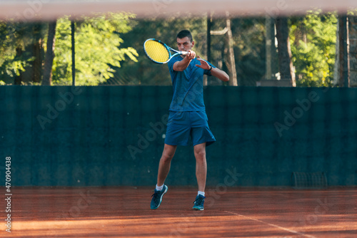 Strong male tennis player observed through the tennis net © qunica.com