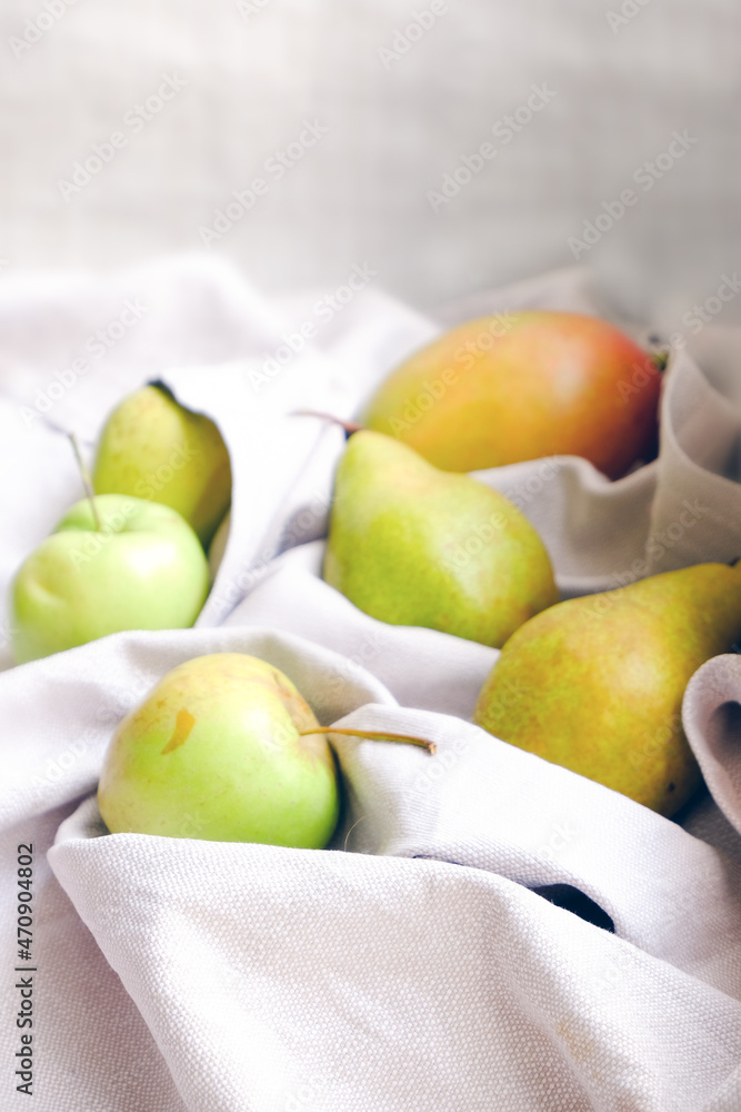 Different green raw organic fruits in a neutral natural napkin. Apples, pears and mango on a simple background. Empty space. Different green raw organic fruits in a neutral natural napkin. Apples, pears and mango on a simple background. Empty space.