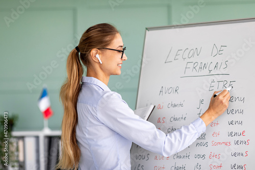 Remote education and tutoring concept. Female teacher writing grammar rules on whiteboard during online French lesson photo