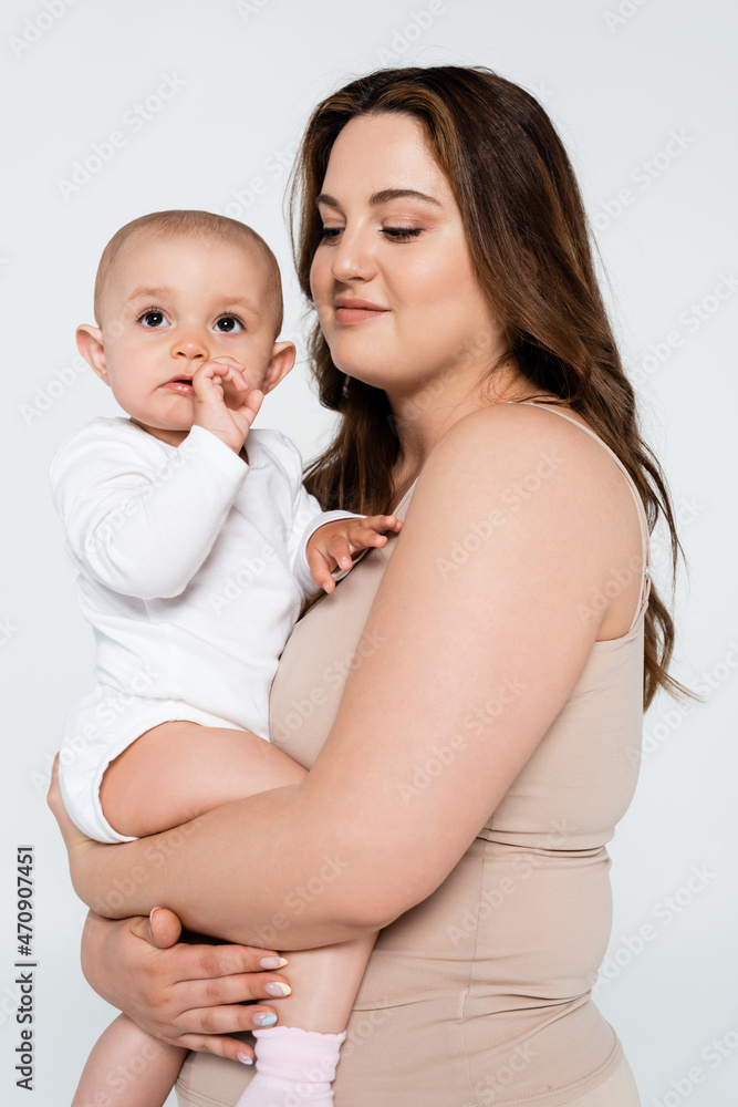 Smiling mother with overweight hugging baby girl isolated on grey. Smiling mother with overweight hugging baby girl isolated on grey.