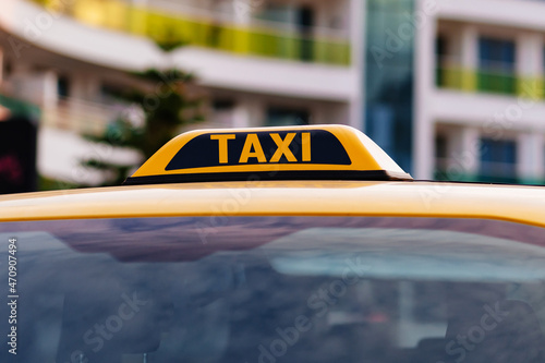 a taxi sign on the roof of a yellow car.