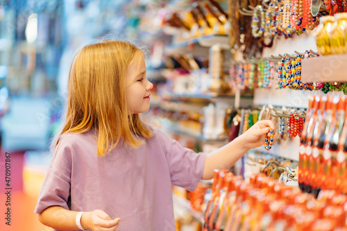 a funny little girl looks with interest at jewelry and souvenirs in the store.  photo