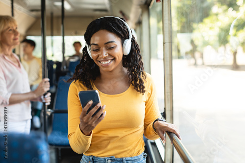 Happy smiling black woman listening music in bus