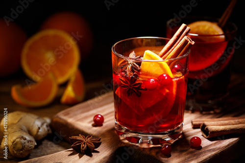 Glass of hot red mulled wine with orange slice and spices of star anise and cinnamon on a wooden table. photo