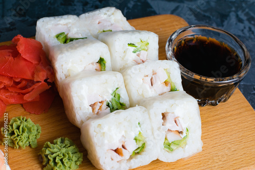 Appetizing rolls with chicken, spinach, red ginger and wasabi on a dark background