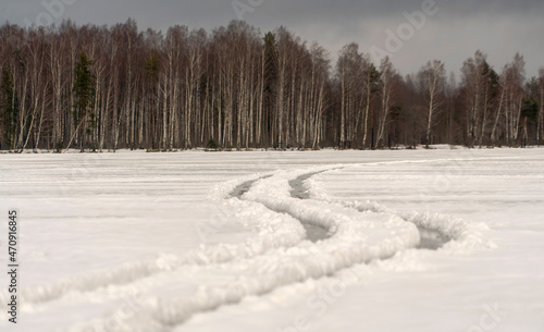 Winding wheel tracks on a frozen lake. Winter day.