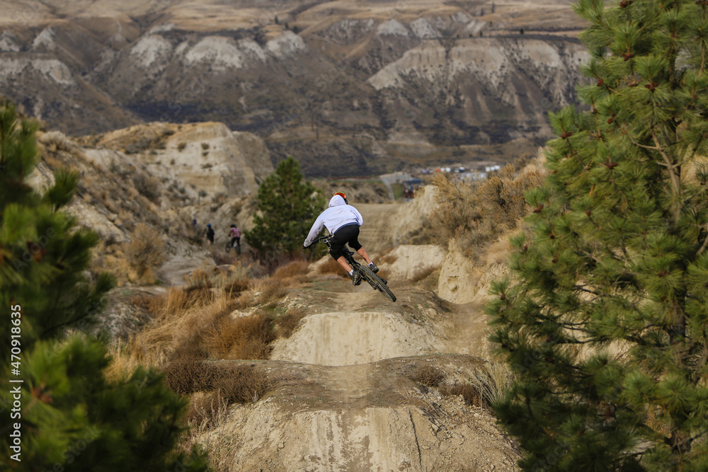 Downhill Mountain Biker at the Kamloops Bike Ranch riding a jump on Wrangler.