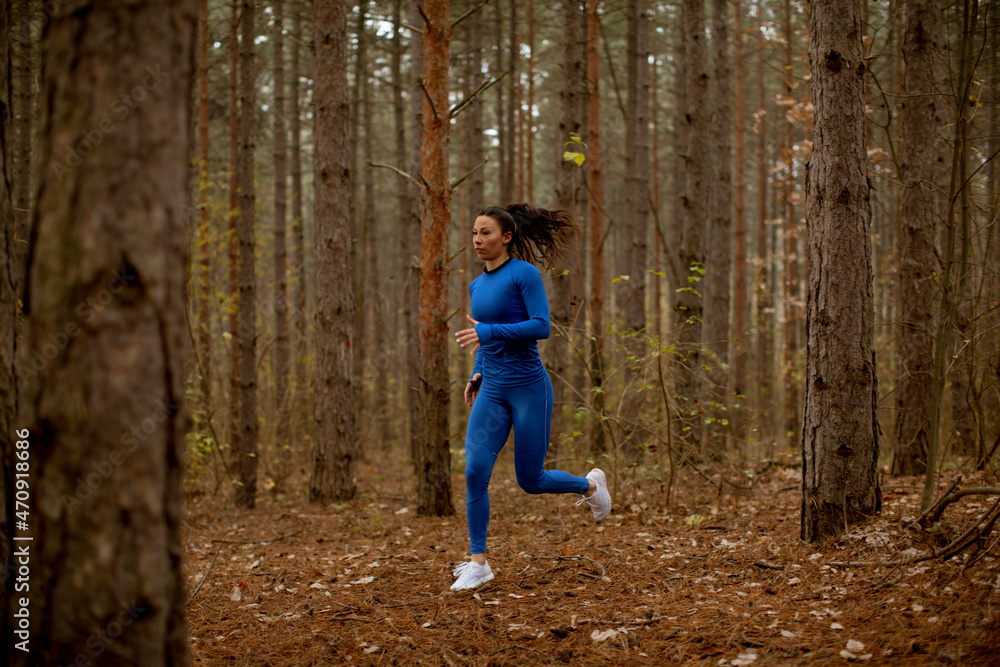 Young woman running on the forest trail at autumn Young woman running on the forest trail at autumn