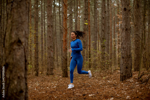 Fototapeta Naklejka Na Ścianę i Meble -  Young woman running on the forest trail at autumn
