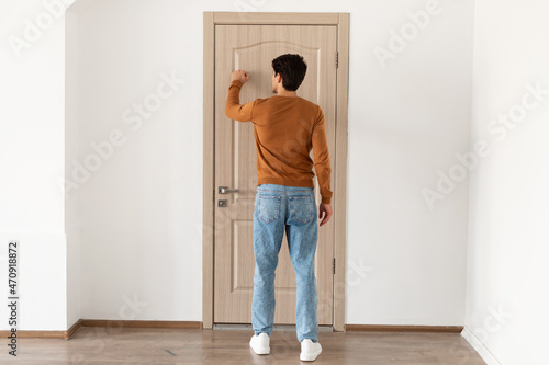Photos Rear back view of man knocking on the wooden door