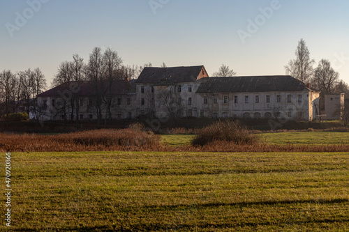 big abandoned manor in Latvia countryside. green yellow pasture or meadow, evening sunset light 