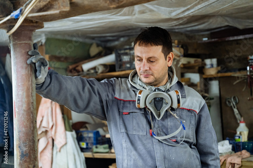 Craft. Joiner and his woodworking tools. Work in the workshop. Creation of household items from wood. Special clothes and gas mask at the carpenr © Aleksey