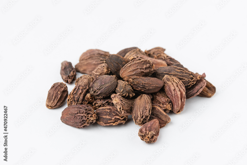 Macro photo of pile black whole dried cardamom seeds on a white background with copy space Macro photo of pile black whole dried cardamom seeds on a white background with copy space