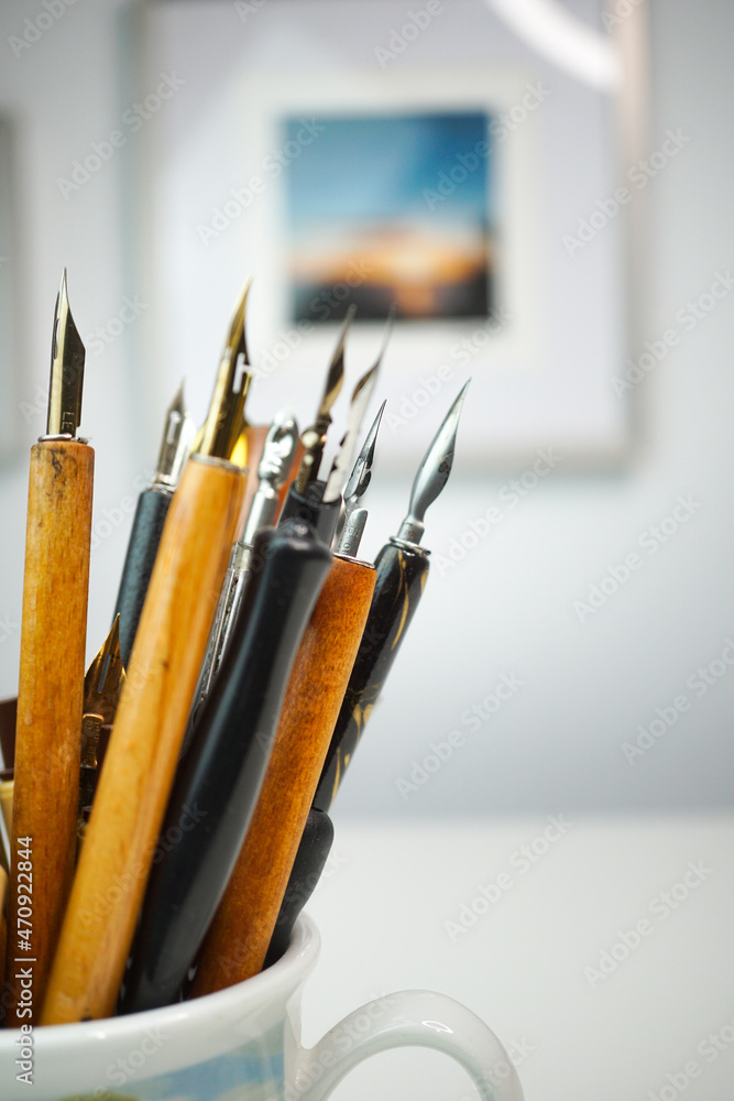 Group of wooden penholders with calligraphy nibs on a colourful mug on a table with nice background_6 Group of wooden penholders with calligraphy nibs on a colourful mug on a table with nice background_6