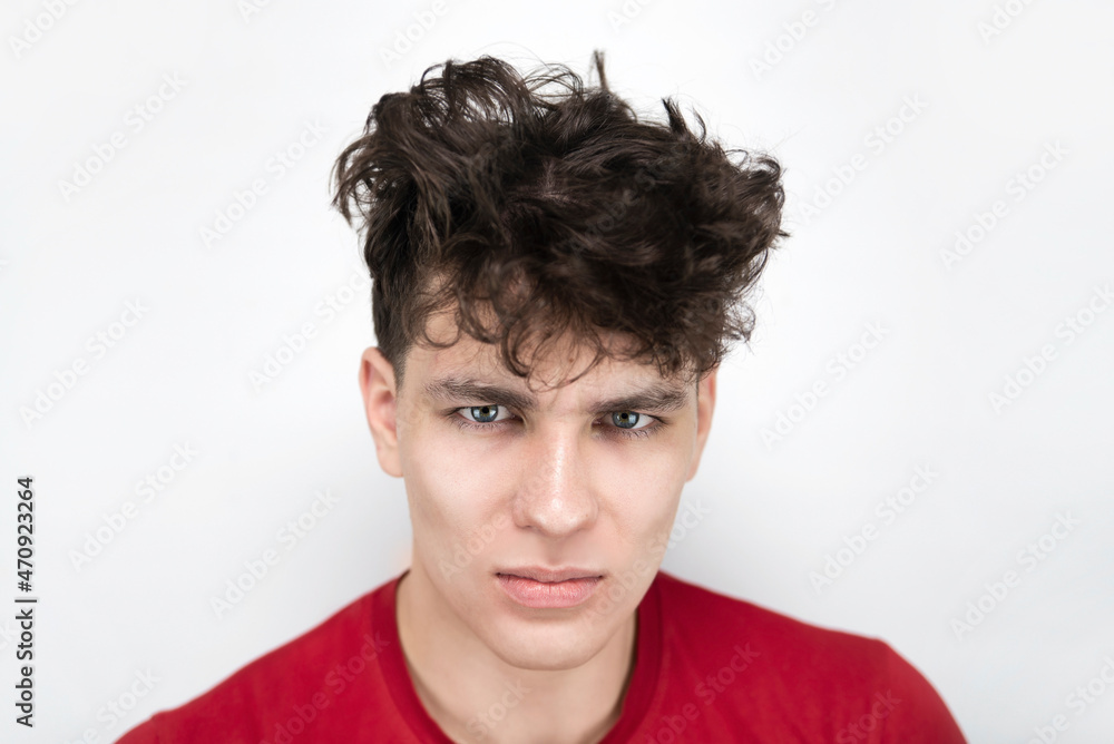 Handsome but sad, a little angry guy teenager 16-18 years old on a light background, the guy has uncombed hair and a gloomy look, a headache Handsome but sad, a little angry guy teenager 16-18 years old on a light background, the guy has uncombed hair and a gloomy look, a headache