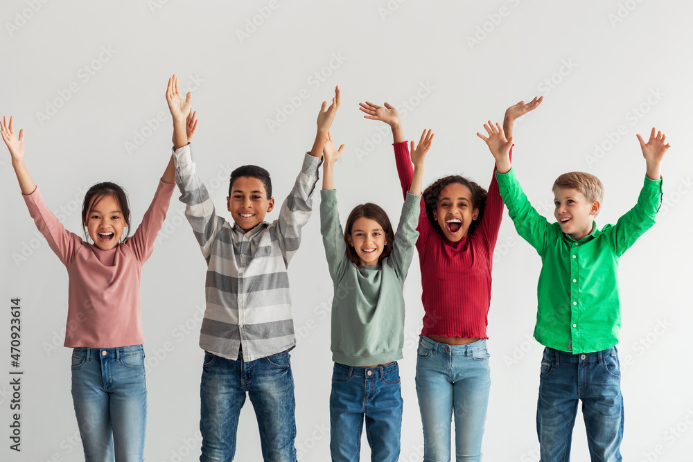Joyful Kids Posing Raising Hands Shouting In Joy, Gray Background Joyful Kids Posing Raising Hands Shouting In Joy, Gray Background