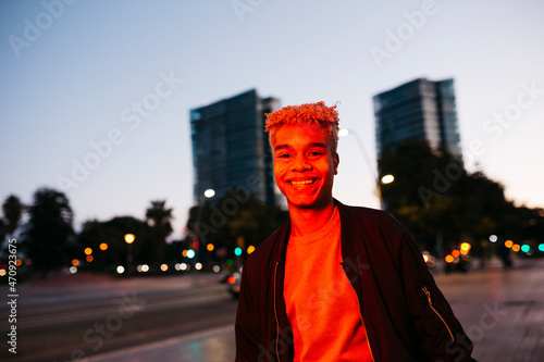 Canvas Print Young latin american male under a red light walking on the street at dusk