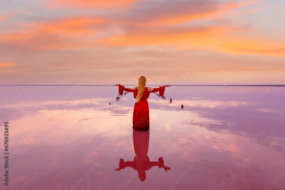 girl in a red long dress posing at sunset on the famous pink salt lake