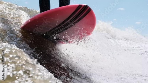 Surfer jumping at speed in waves using wakeboard splashing water drops to camera