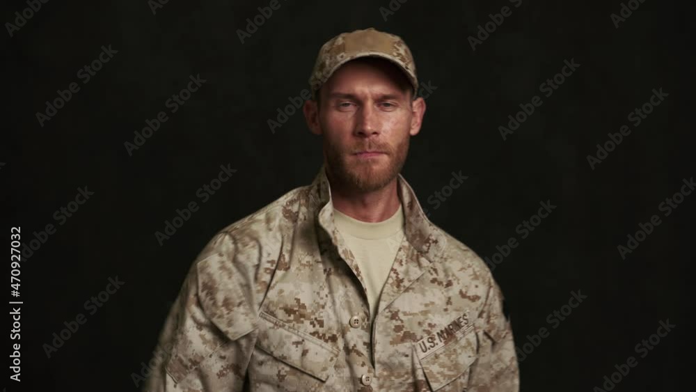Serious military man salutes and looking at the camera in black studio Serious military man salutes and looking at the camera in black studio