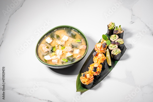 Sushi set and miso soup on white background. Maki roll for lunch offer or business lunch. Japanese traditional healthy food. KETO diet, low-carb sushi without rice. Restaurant menu. Copy space