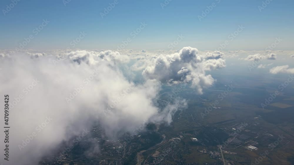 Aerial view from airplane window at high altitude of earth covered with white puffy cumulus clouds Aerial view from airplane window at high altitude of earth covered with white puffy cumulus clouds