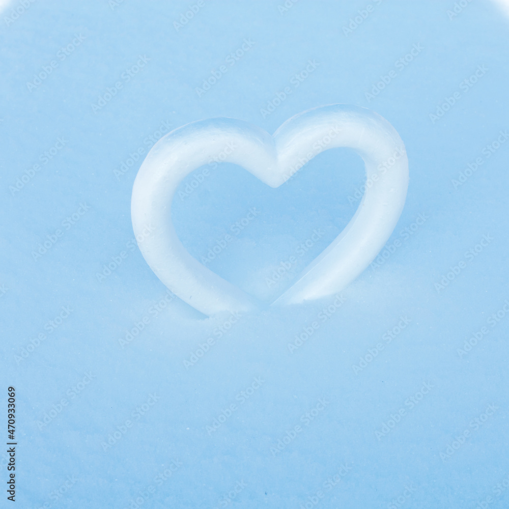 Styrofoam heart symbol on white snow sparkling in the sun. The basis for the postcard. Place for an inscription.