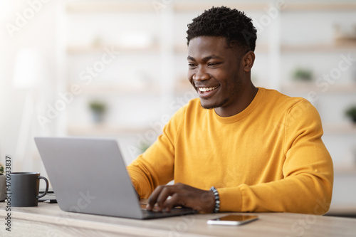 Canvas Print Successful black guy project manager typing on laptop keyboard