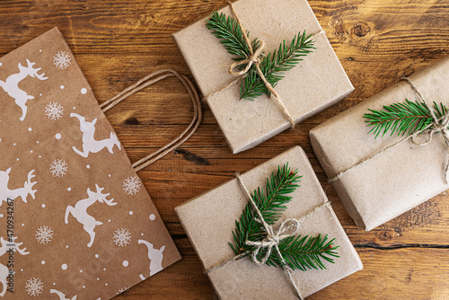 Christmas gifts wrapped in eco-friendly paper and a gift craft bag on a wooden table. Christmas flat lay. Festive background for the New Year's sale