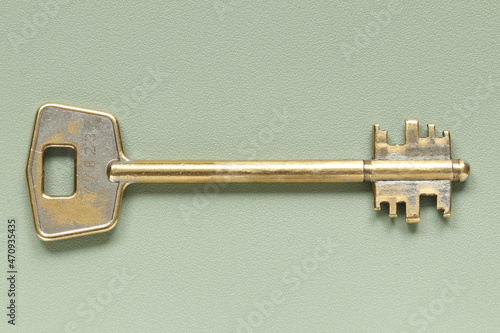 Old key from the door lock on a green background. Old key.  © homeworlds