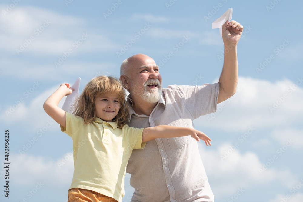 Grandfather and son playing with toy paper plane against summer sky background. Child boy with dreams of flying. Family Relationship Grandfather and child. Grandfather and son playing with toy paper plane against summer sky background. Child boy with dreams of flying. Family Relationship Grandfather and child.