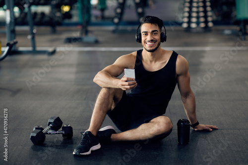Handsome Arab Athlete Relaxing With Smartphone After Training In Gym