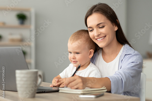 Online Education. Young Woman Holding Baby And Study With Laptop At Home
