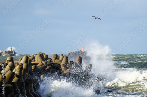 during stormy weather, large waves crash against the concrete blocks of a breakwater