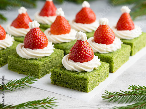 Green spinach cakes with cream cheese frosting and fresh strawberries (santa hat shape). Creative christmas and new year dessert.