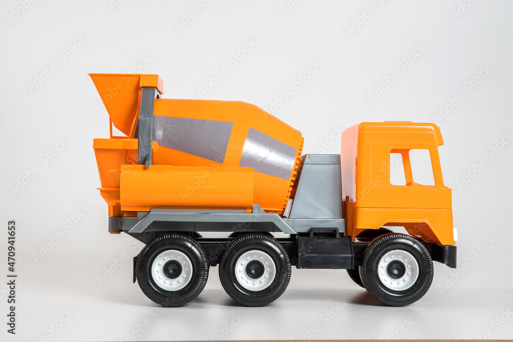 Multi-colored plastic children's toy cars on a white background. Orange concrete truck. Multi-colored plastic children's toy cars on a white background. Orange concrete truck.