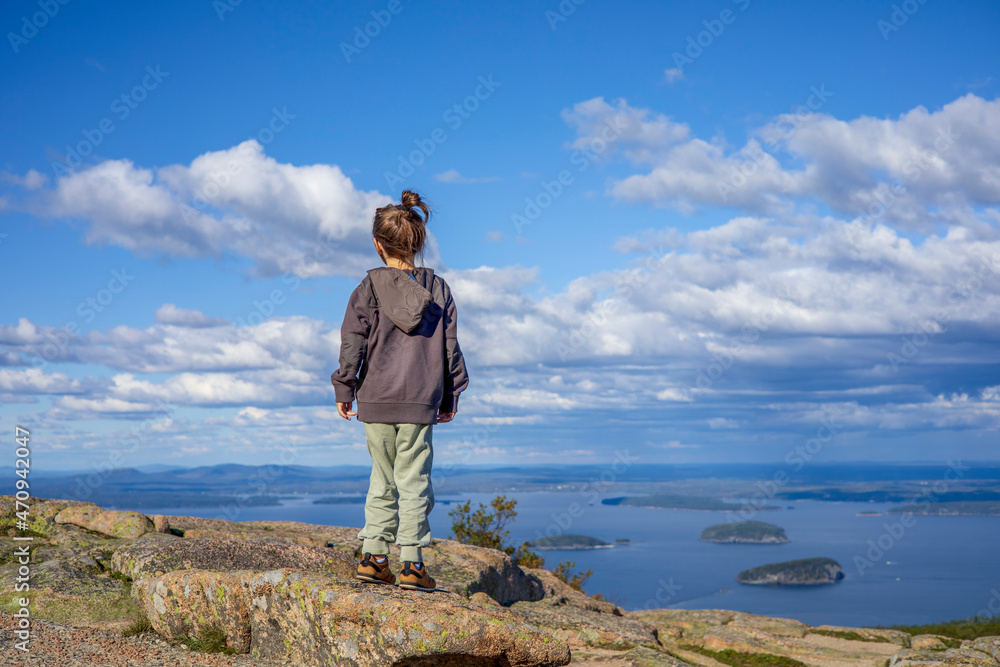 Obraz premium Little girl standing on top of a rock on a mountain