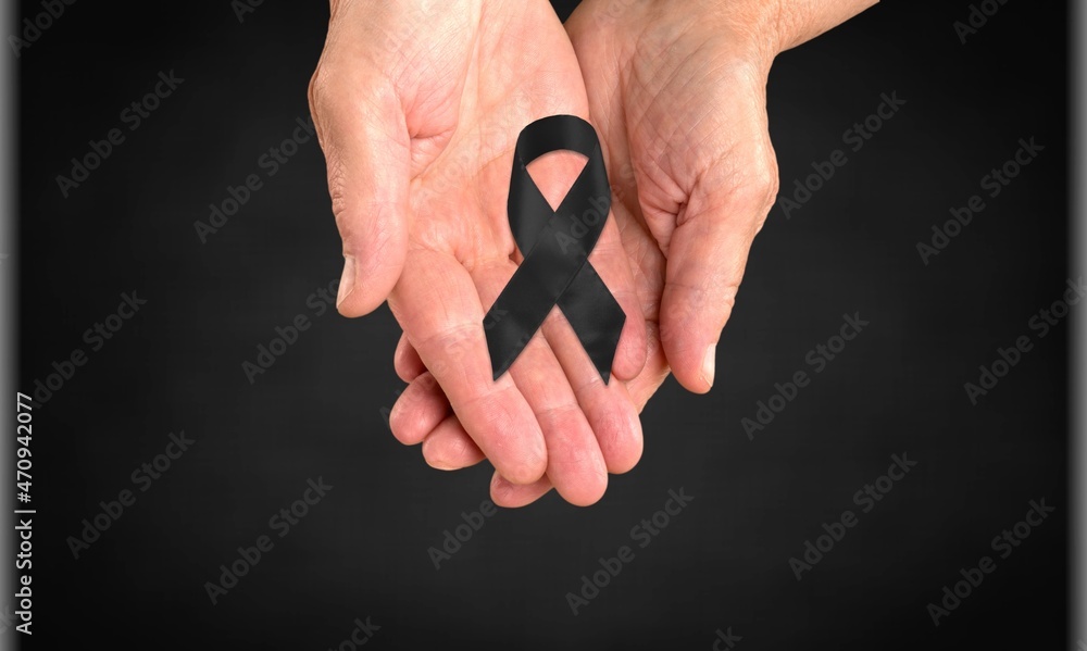 Fototapeta premium Woman hands with black funeral ribbon on dark background