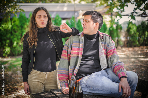 Relaxed and smiling happy couple, smoking ganja joint in park