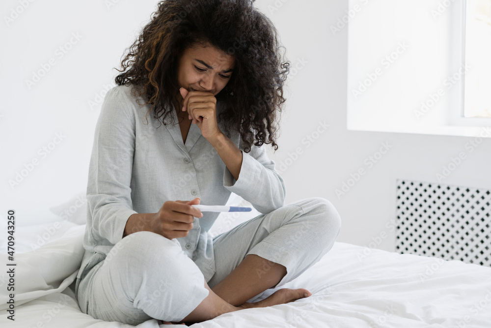 Dark skinned woman crying, look at pregnancy test Dark skinned woman crying, look at pregnancy test