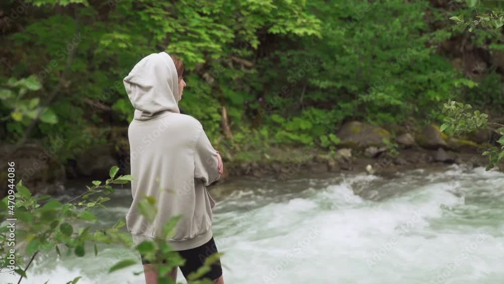 A young girl of European appearance stands in the middle of the forest by a mountain river. Outdoors. Tourism A young girl of European appearance stands in the middle of the forest by a mountain river. Outdoors. Tourism